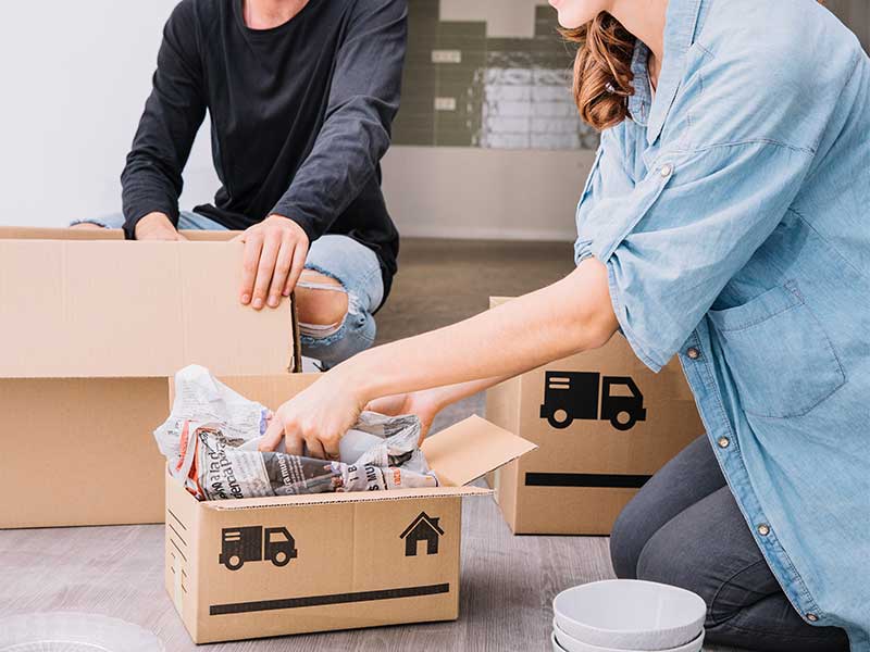 People packing things into boxed that they are using to move.